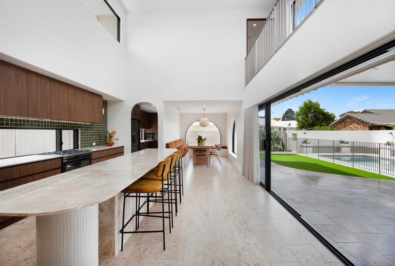 Queensland kitchen with timber cabinetry, a long stone island and open garden views